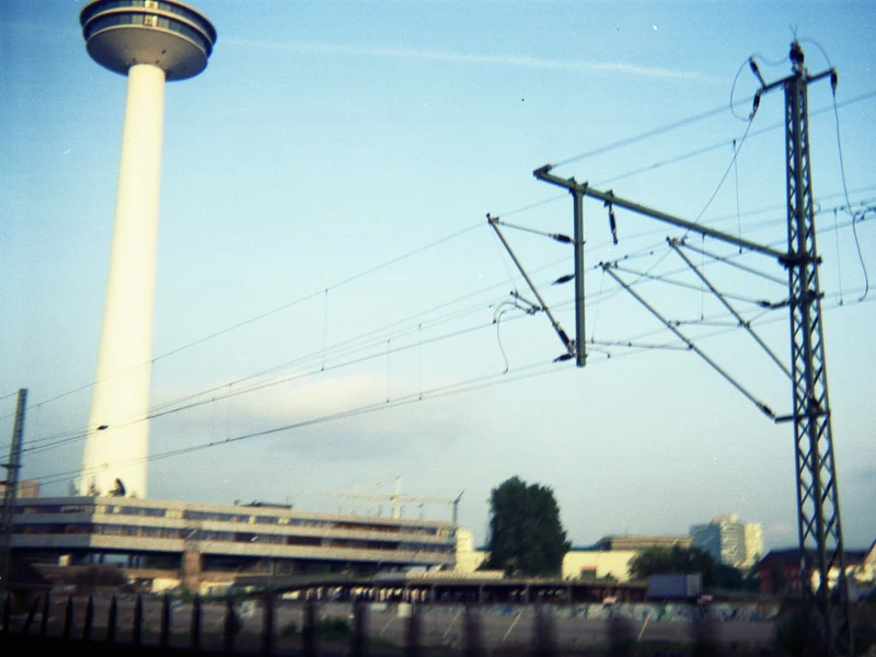 A tall observation tower next to railway power lines against a blue sky.