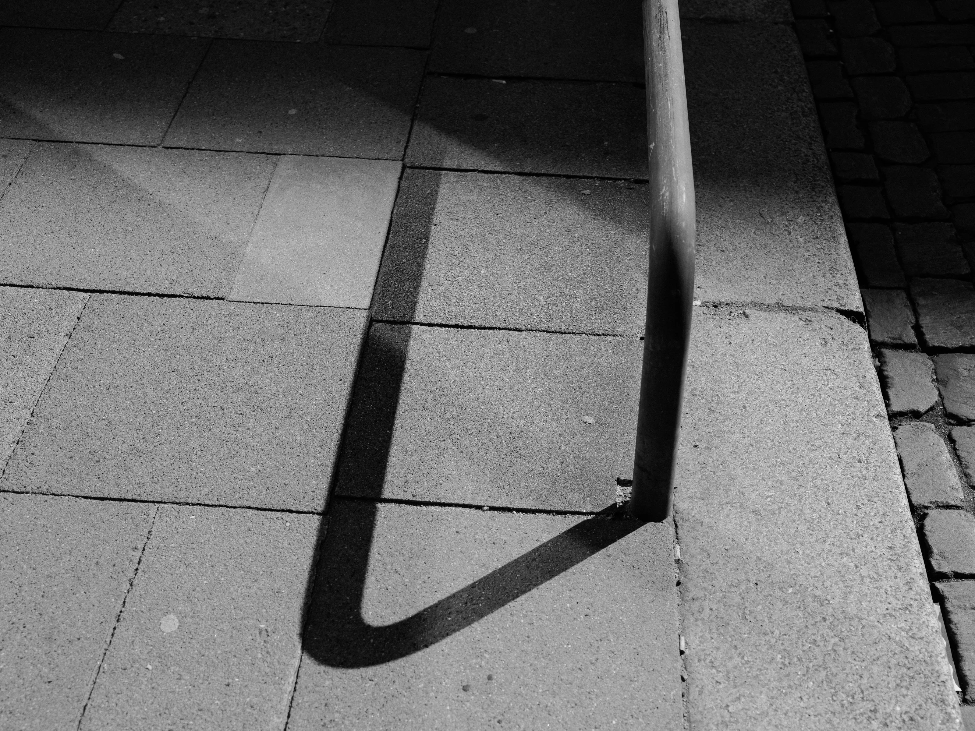 A shadow of a railing cast on a tiled sidewalk.