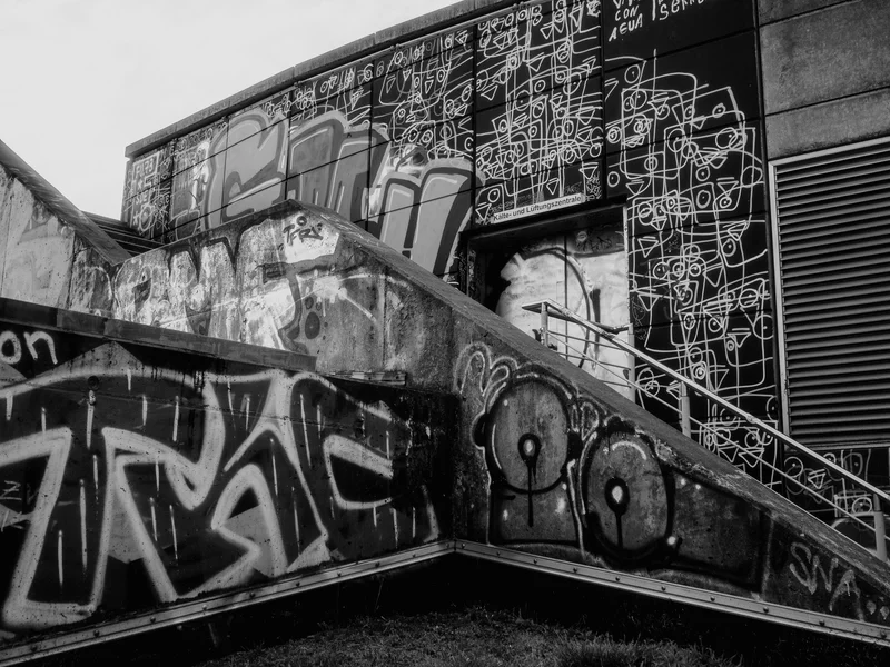 Black and white photo of a building wall covered in abstract graffiti art.
