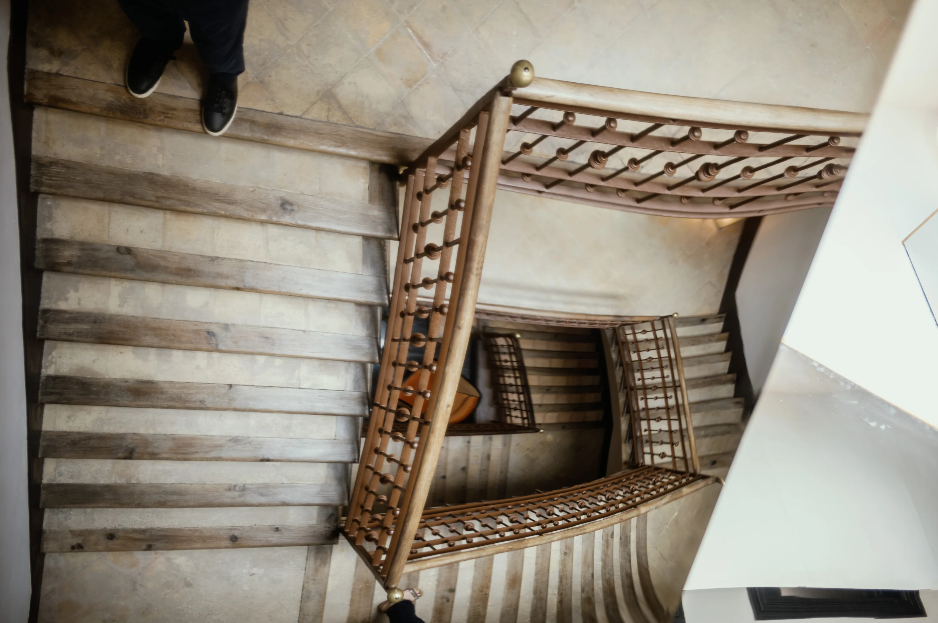 A spiral staircase viewed from above, showcasing multiple wooden steps and railings.