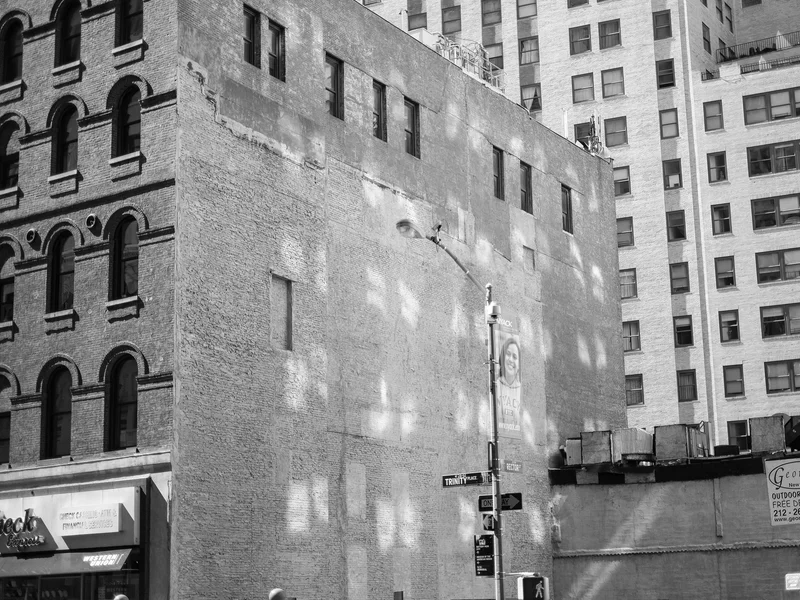Urban scene with old and modern buildings, featuring a street lamp and signs at an intersection.