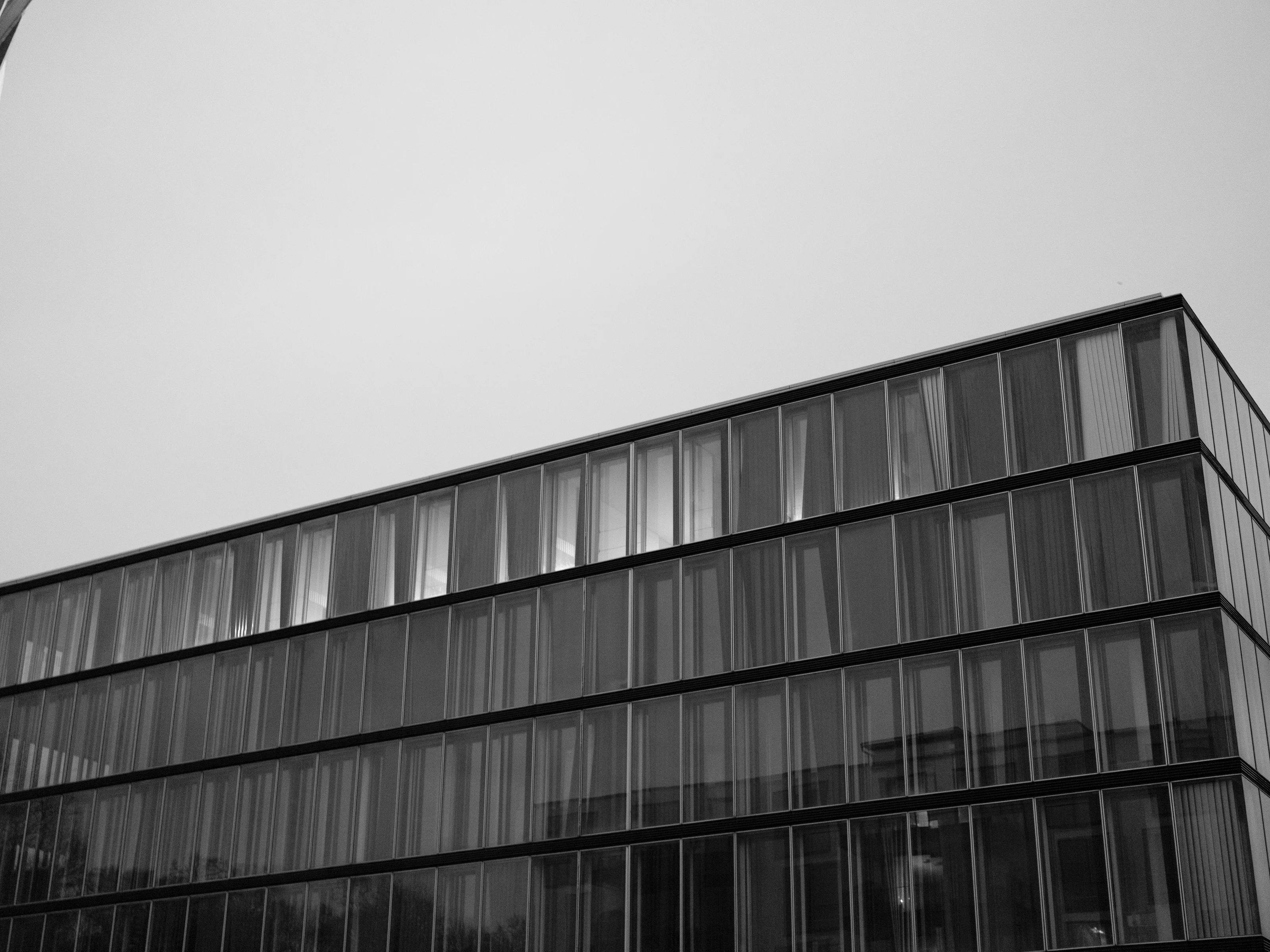 Black and white image of a modern glass building facade against a clear sky.