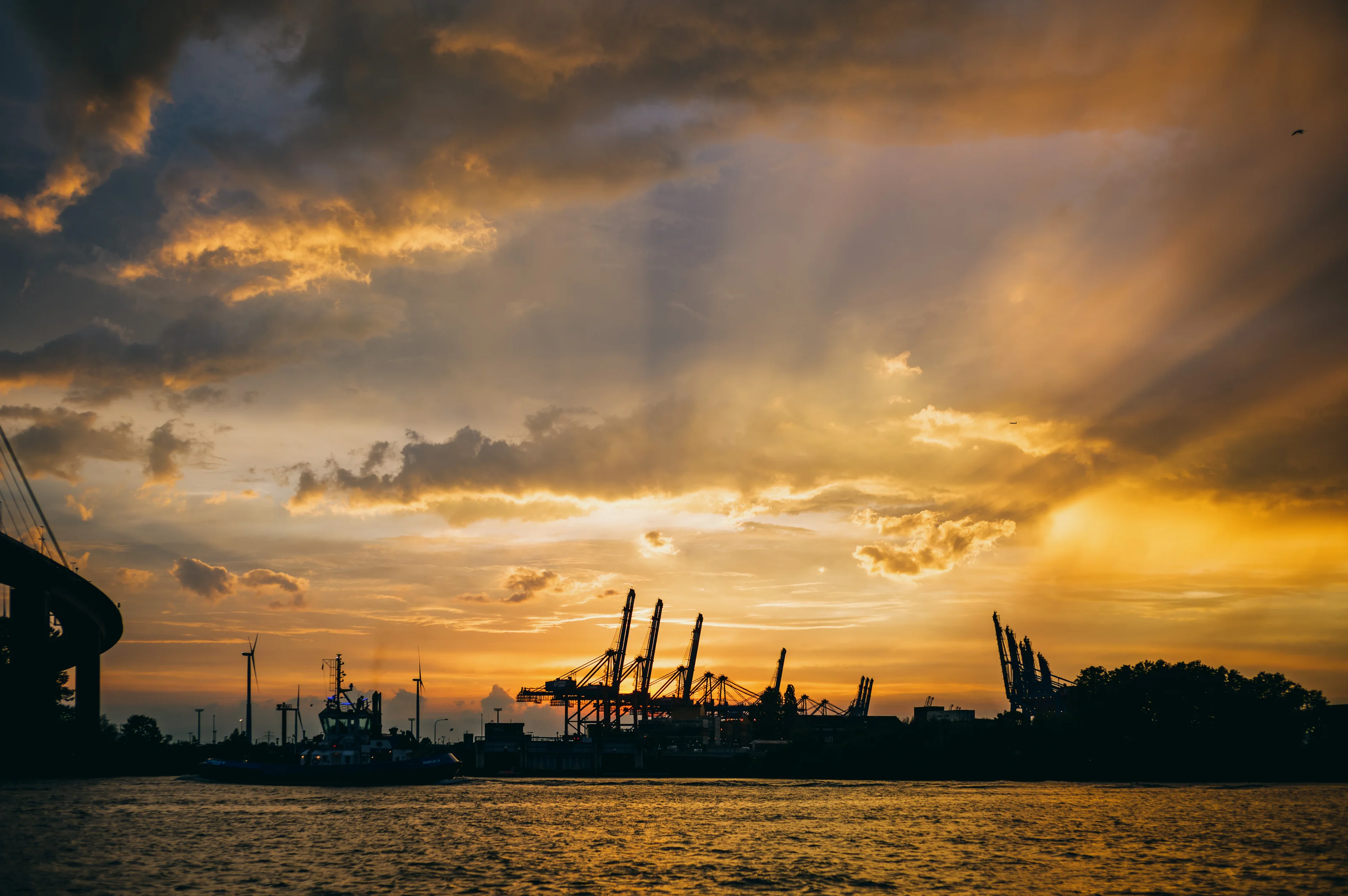 Harbor cranes silhouetted against a dramatic sunset sky.