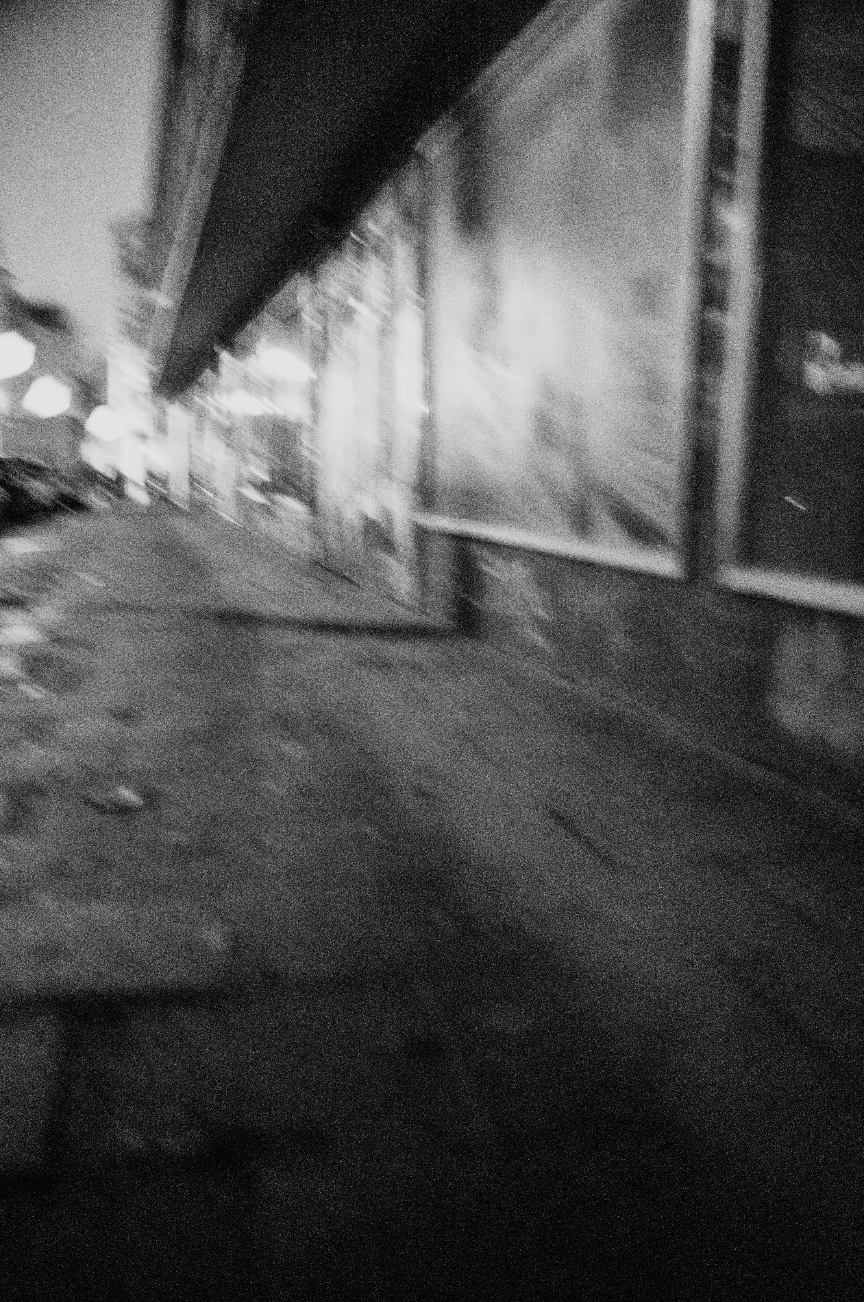 Blurred black and white image of an urban street at night.