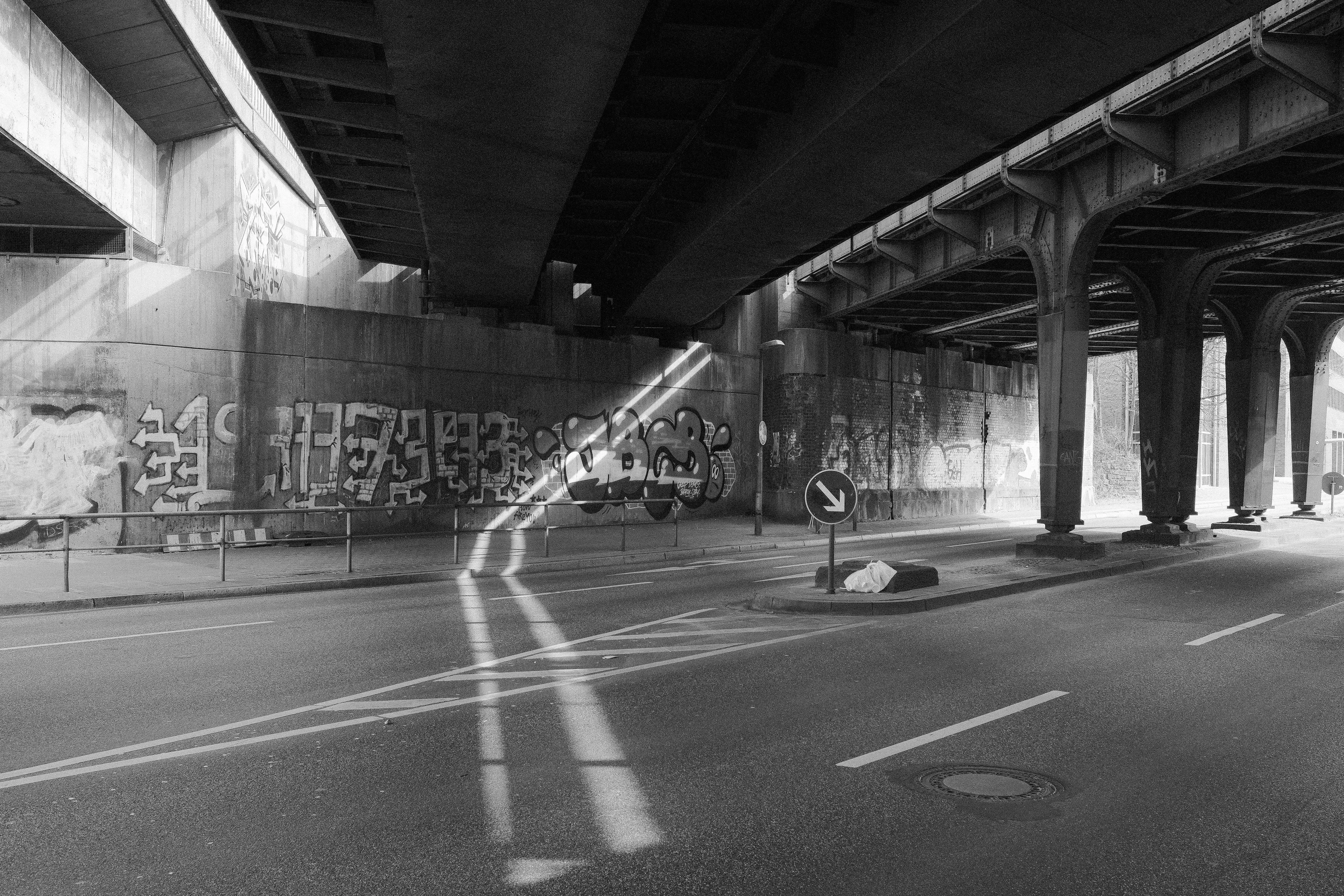 Underpass with graffiti on the walls and sunlight streaming through gaps.