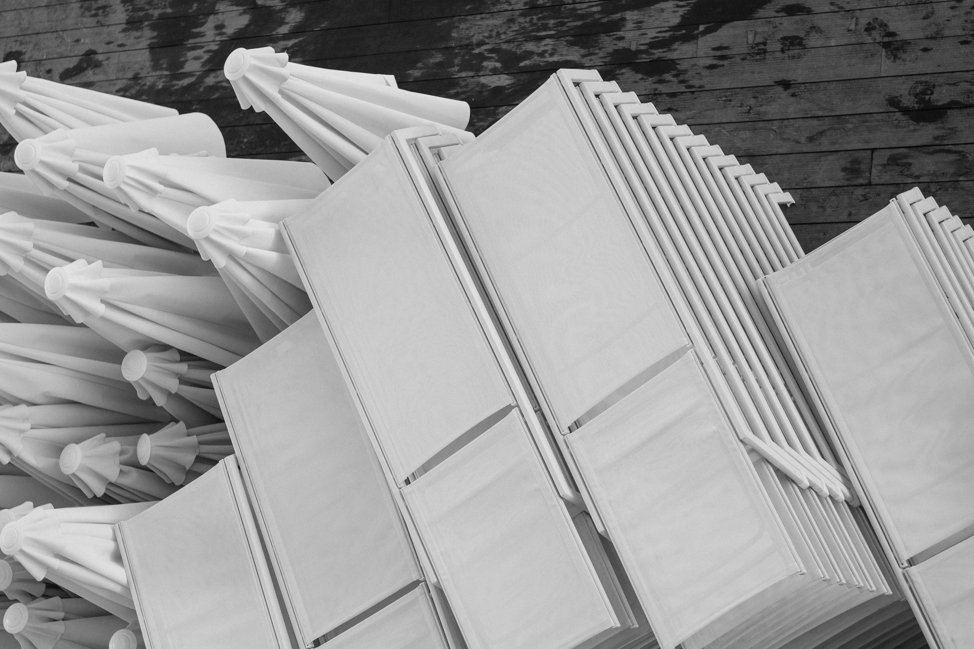 Folded white umbrellas stacked against a textured wooden deck.