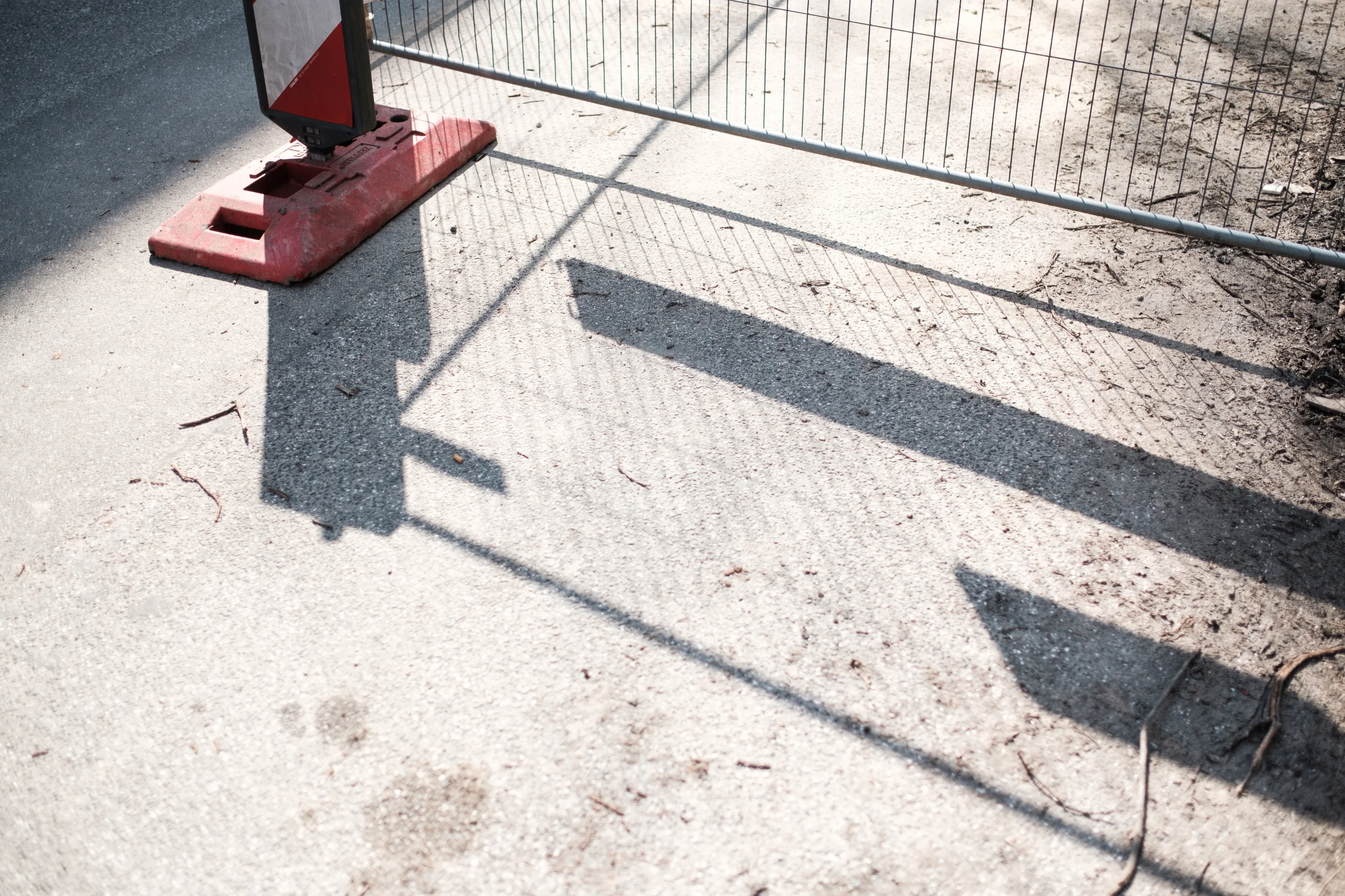 Shadow of a construction barricade on a concrete surface.