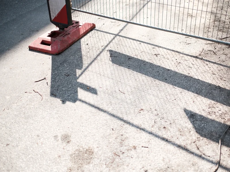 Shadow of a construction barricade on a concrete surface.
