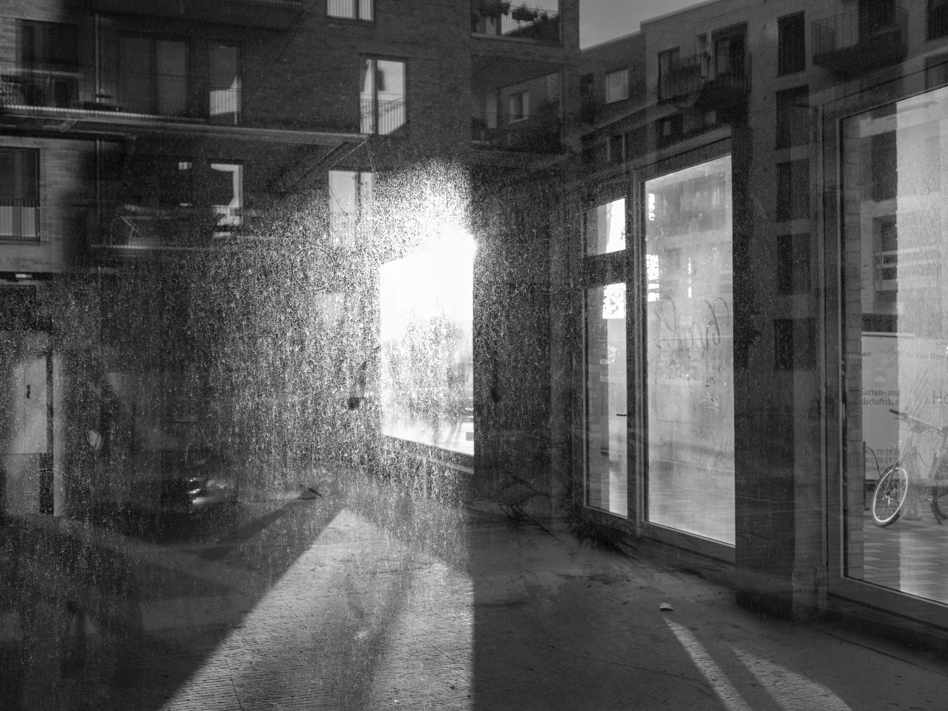 Reflections of buildings and a bicycle on a wet glass surface.