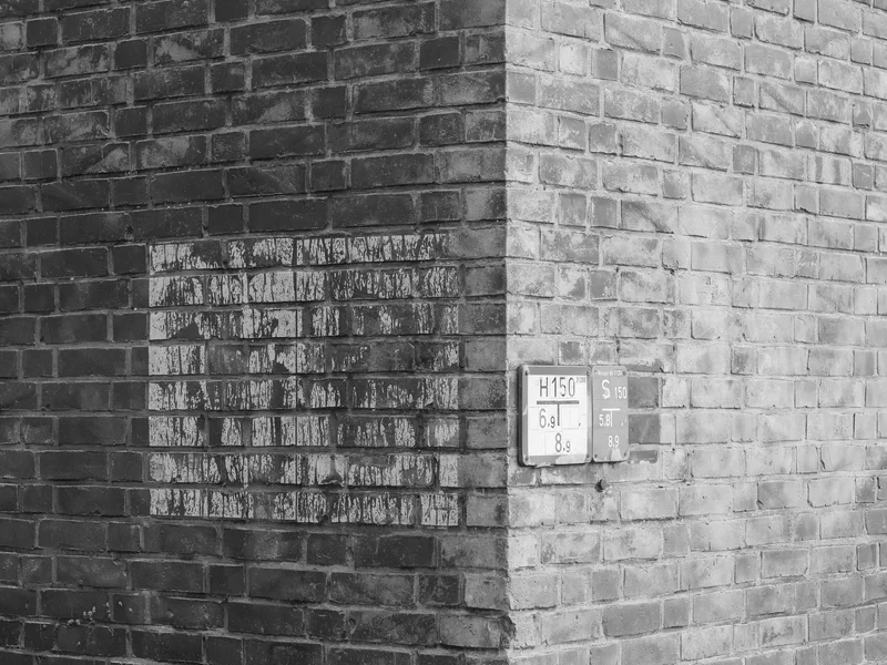 Corner of a brick wall with painted and mounted signs.