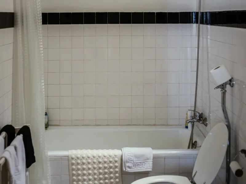 A bathroom with a white tiled bathtub and a toilet in front.