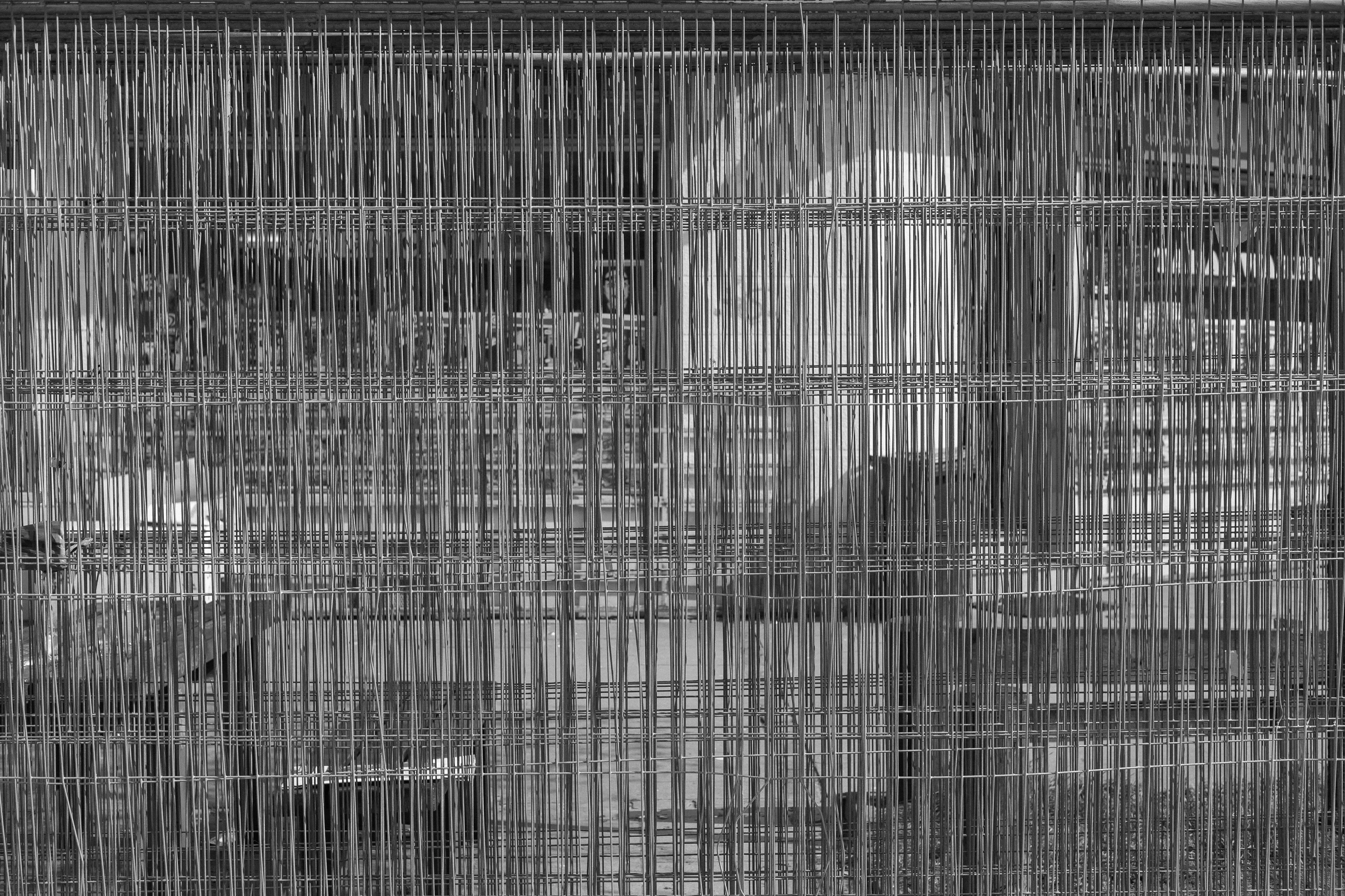 A dense metal wire grid in grayscale with intersecting vertical and horizontal lines.