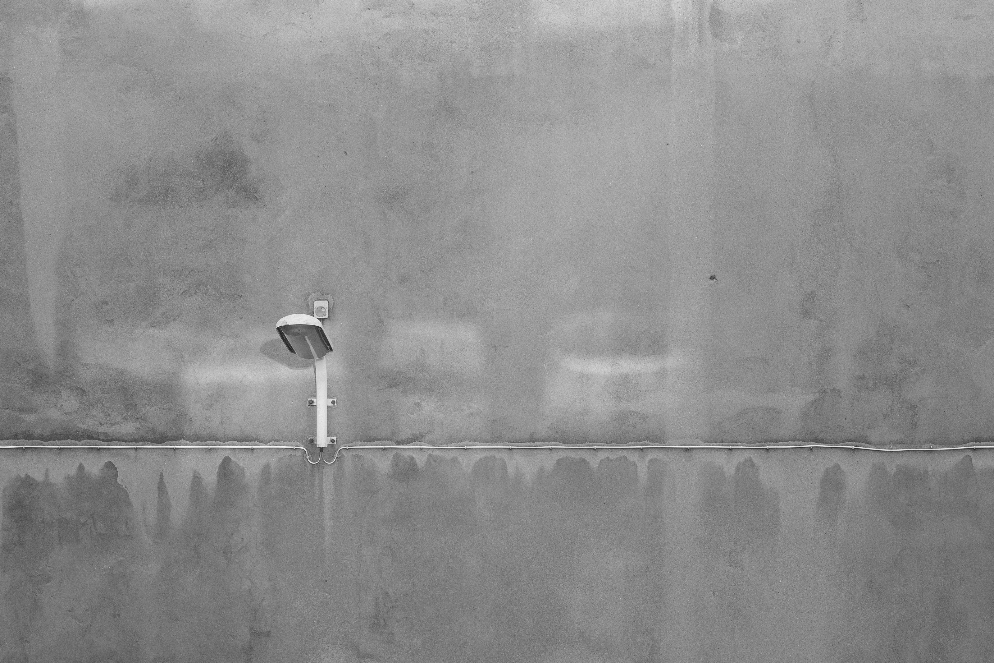 A single wall-mounted light fixture on a textured concrete wall.