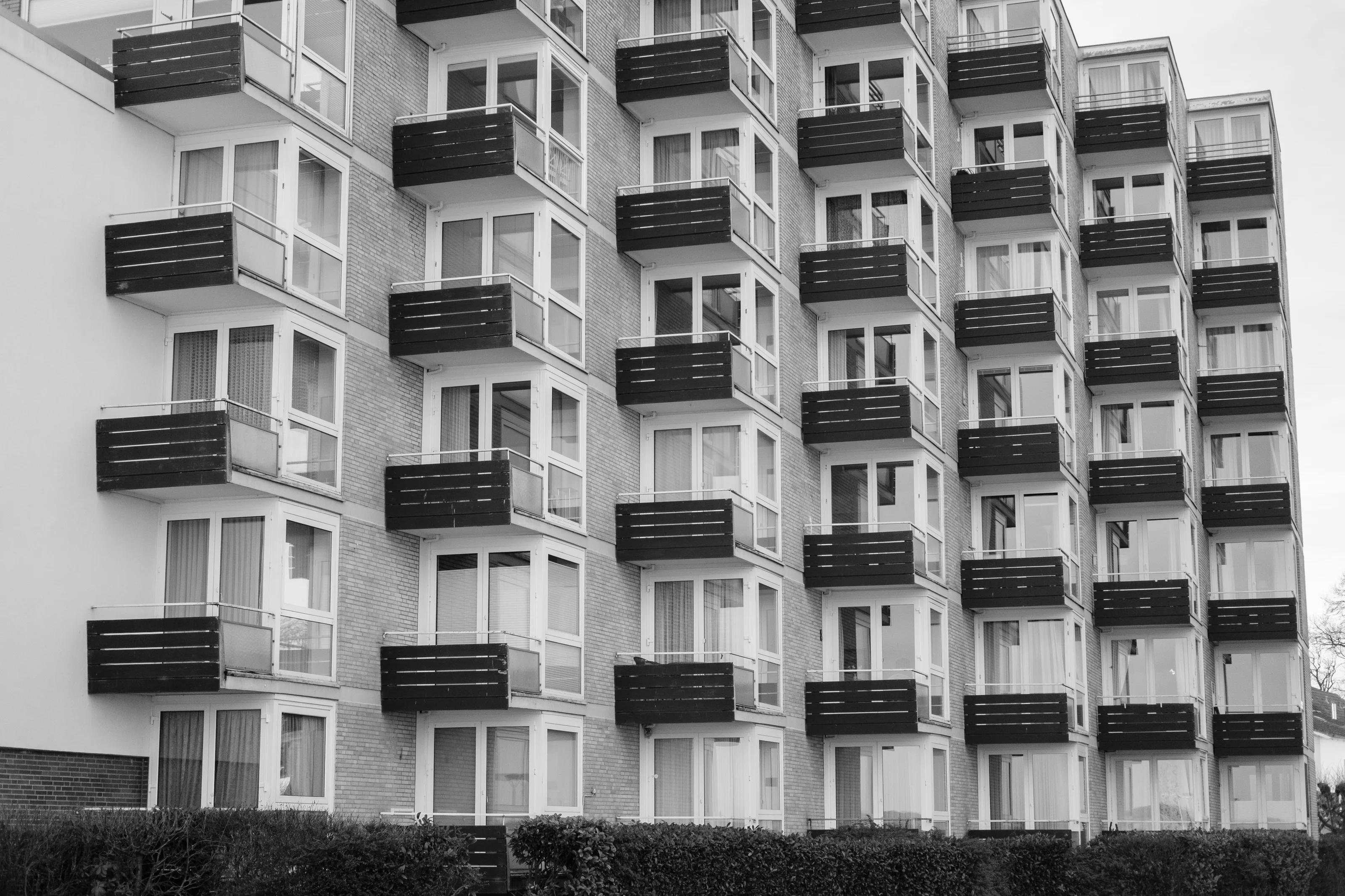 A black and white photo of a modern apartment building with multiple balconies.